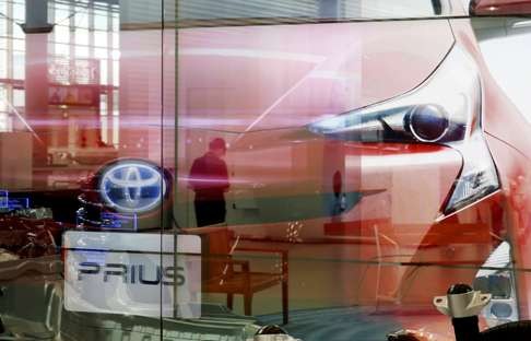 A woman is reflected on a screen showing Toyota Motor Corp's Prius hybrid car at the company's showroom in Tokyo. Photo: Reuters
