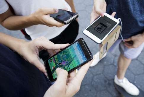 Three people play Pokemon Go on their smartphones. Photo: EPA