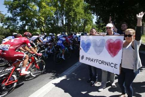 The main pack of riders pass supporters holding a banner in tribute to victims of the truck terrorist attack in Nice. Photo: EPA