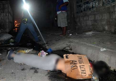 The dead body of a suspected drug dealer lies on the ground with a placard reading ‘Chinese Drug Lord’ in Manila on July 1. Photo: AFP