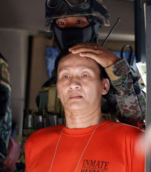 Convicted Chinese drug dealer Peter Co is escorted by a police commando at the New Bilibid Prison after jail guards were removed from duty. Photo: EPA