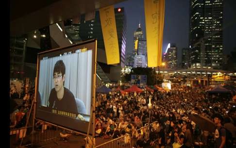 Pro-democracy protesters watch formal talks between student protest leaders and city officials on a video screen near government headquarters on October 21, 2014. Photo: Reuters