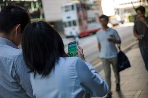 Pedestrians play Pokemon Go on the first day of its release in Hong Kong on July 25. Photo: EPA