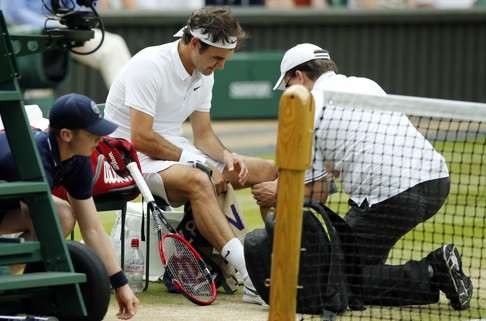 Roger Federer of Switzerland receives medical attention during his men's semifinal singles match against Milos Raonic of Canada at the Wimbledon Tennis Championships in London. Federer says he will miss the Rio Olympics and the rest of the tennis season to protect his surgically repaired left knee. Photo: AP