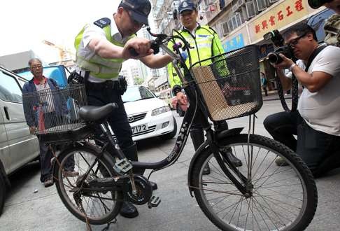 Police arrest a man for riding on a bike installed with an electric motor in Sham Shui Po. Photo: Dickson Lee