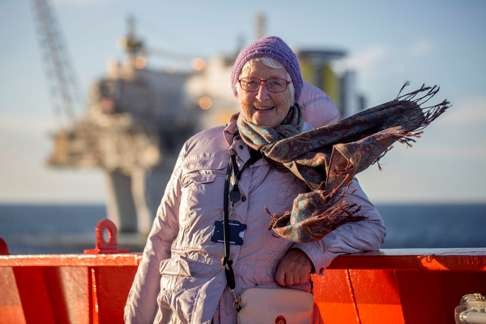 A woman poses for a photo in front of oil platform.