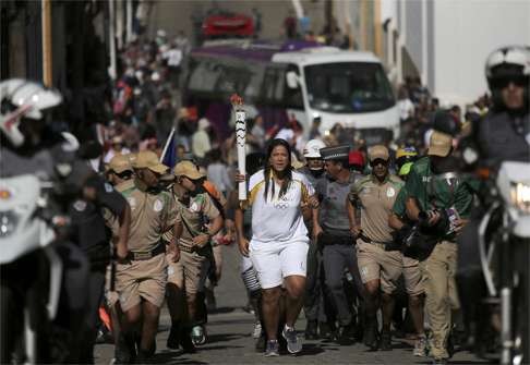 Jessica Cruz Santos, a former volleyball player, carries the Olympic torch in the streets of Sao Luiz do Paraitinga, Brazil. The torch became a target for demonstrators this week. Photo: Reuters