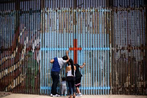 A family talks with relatives through the US-Mexico border fence in Playas de Tijuana, in Tijuana, northwestern Mexico. From immigration to trade liberalisation, economic pressures on a beleaguered middle class contradict the core promises of globalisation. Photo: AFP