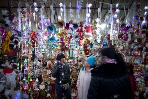 A shopkeeper tends to customers at a stall selling Christmas decorations in Beijing. Photo: AFP