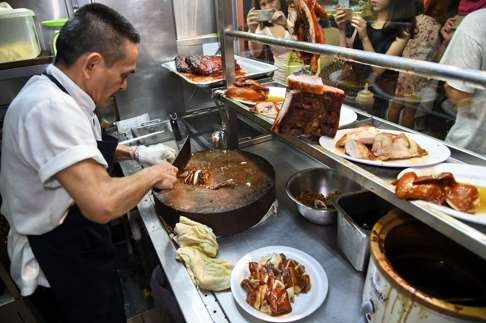 Chan Hon Meng chops braised chicken at his Hong Kong Soya Sauce Chicken Rice and Noodle stall in Singapore. Photo: AFP