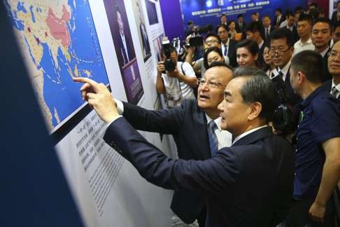 Foreign Minister Wang Yi (foreground) views posters showing details of Xinjiang’s economic development at the 17th Lanting Forum in Beijing. The theme of the forum is “Silk Road: Opportunities and future to boost the Chinese Silk Road Economic Belt”. Photo: EPA