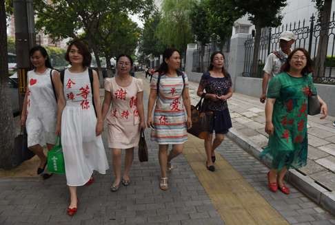 Wives of detained rights lawyers wear the names of their husbands as they walk away from an office of the Supreme People’s Procuratorate in July after attempting to hand in a formal complaint about being denied access to them, in Beijing. Photo: AFP