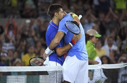 Juan Martin Del Potro (right) hugs Novak Djokovic t the net after winning the match. Photo: Reuters