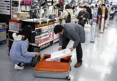 Chinese tourists pack shopping into a suitcase at a department store in Tokyo. Photo: Reuters