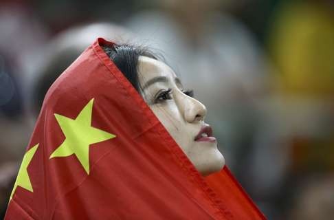 A Chinese supporter wraps herself in a national flag after China won the bronze at the men’s team gymnastics finals. Photo: Reuters