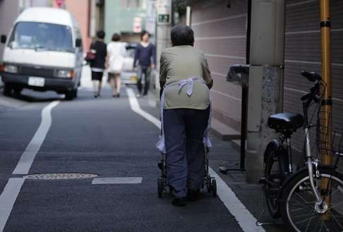 A woman pushes a trolley in the Sugamo Jizo-dori shopping area in Tokyo, Japan. The Japanese are still struggling with how to get the economy going. Photo: Bloomberg