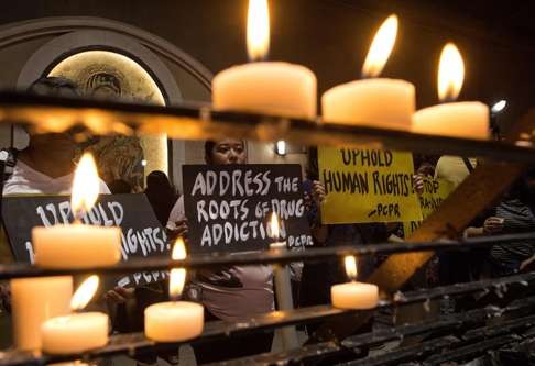 Human rights advocates hold placards condemning extra judicial killing after a mass at the Redemptorist Church in Manila. Photo: AFP