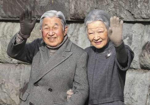 Japan's Emperor Akihito and Empress Michiko wave to locals as they take a walk on a coast near the Hayama Imperial Villa in Hayama, near Tokyo. Photo: AP