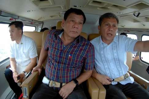 President Rodrigo Duterte (centre) conducts an inspection inside a helicopter during an aerial survey of flood-hit communities in Metro Manila. Photo: EPA