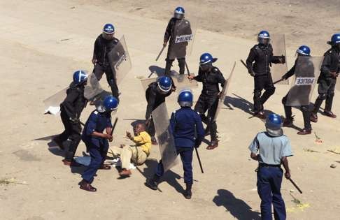 Zimbabwean riot police surround a protester during a demonstration against the introduction of bond notes by the Reserve Bank of Zimbabwe in Harare. Photo: AP