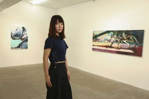 Artist Ashlee Ip with her oil-on-canvas works Adventurist (right) and Jim2 oil at Gallery Exit in Aberdeen. Photo: Edmond So