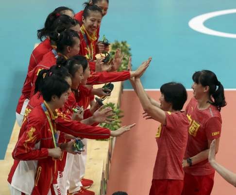 Lang Ping and her assistant, Lai Yawen, congratulate their players at the medal ceremony. Photo: Reuters