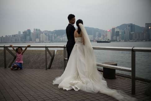 A couple pose for a wedding photo on a promenade overlooking Victoria Harbour. A significant proportion of Hong Kong people seek a spouse from outside the city because of the difficulties of finding a local partner. Photo: AFP