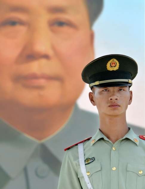 An armed police officer stands guard in front of the portrait of Mao Zedong in Beijing's Tiananmen Square. Photo: Kyodo