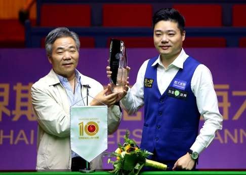 Ding receives the trophy after securing his second win at the Shanghai Masters.