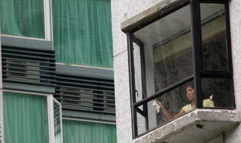 A domestic helper cleans a window in an upmarket flat. Photo: SCMP Pictures