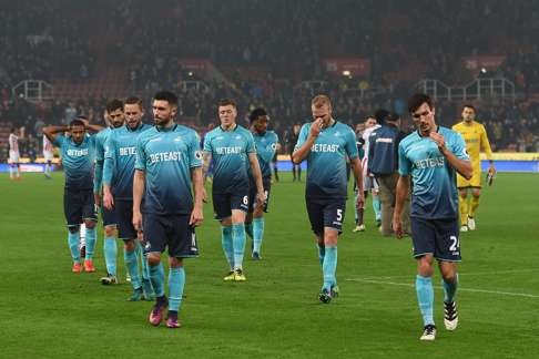 Swansea players look despondent as they leave the pitch following the defeat against Stoke. Photo: AFP