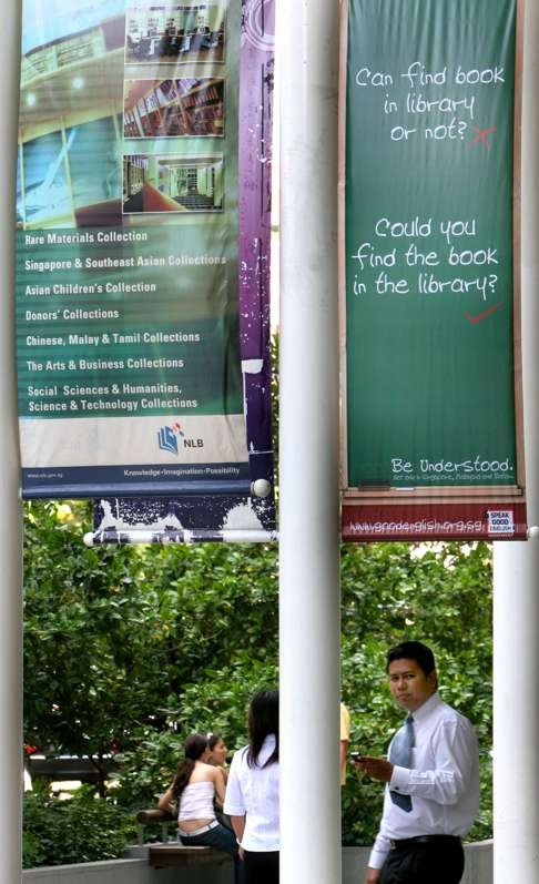 People walk under a banner promoting the use of correct spoken English outside the Singapore National Library. The country’s leaders have tried to suppress the use of Singlish. Photo: AP