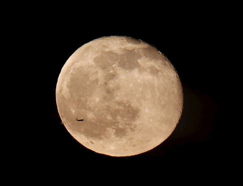 A silhouetted airplane flies past a full moon over Istanbul, Turkey on May 5, 2015. Photo: Osman Orsal/REUTERS