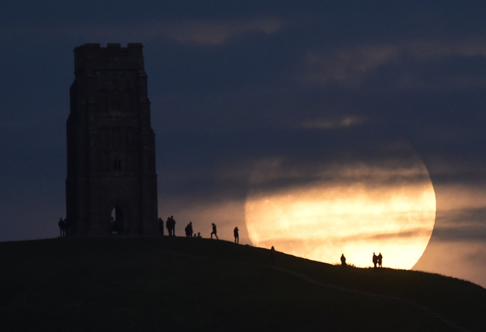 The moon rises near Glastonbury Tor a day before the 