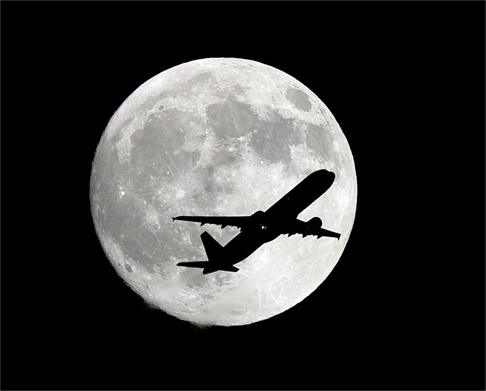 A plane heading to Los Angeles International Airport crosses the Harvest Moon in Whittier on Thursday, September 15, 2016. Photo: Nick Ut/AP