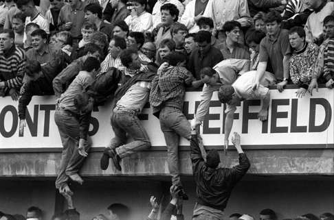 Liverpool fans climb the terraces in a desperate bid to escape being crushed at the Leppings Lane end during the 1989 Hillsborough disaster.