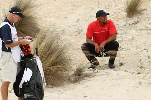 Woods and caddie Joe LaCava consider his second shot on the third hole during the final round of the Hero World Challenge. Photo: AFP