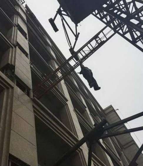 The construction worker hangs suspended from the safety rope after falling from the crane at the building site in Zhejiang province. Photo: SCMP Pictures