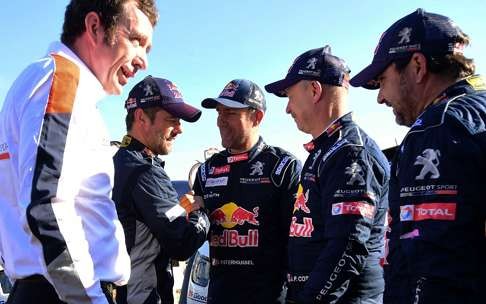 Peugeot's driver Stephane Peterhansel (centre) shakes hands with second-placed Sebastien Loeb. Photo: AFP