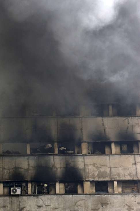 An Iranian firefighter, bottom left, works in operations to extinguish fire of the Plasco building. Photo: AP