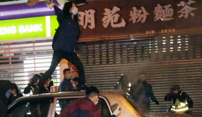 Masked rioters in Mong Kok besiege an empy taxi. Photo: Edward Wong/SCMP
