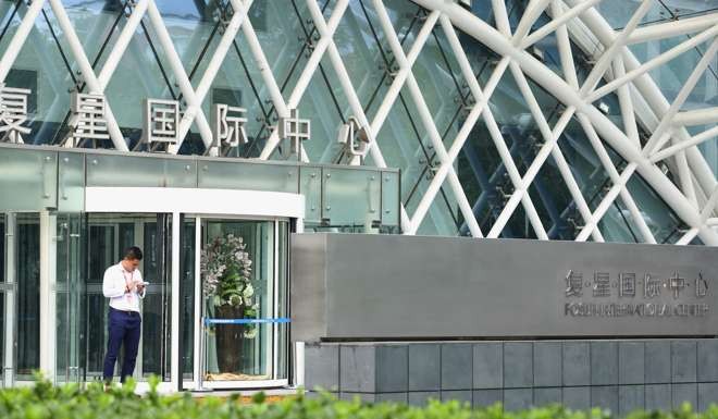 A man stands outside the headquarters building of Fosun International in Beijing. Photo: AFP