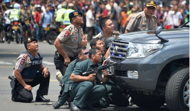 Indonesian police take position behind a vehicle as they pursue suspects after a series of blasts hit the Indonesia capital Jakarta on January 14, 2016. Photo: AFP