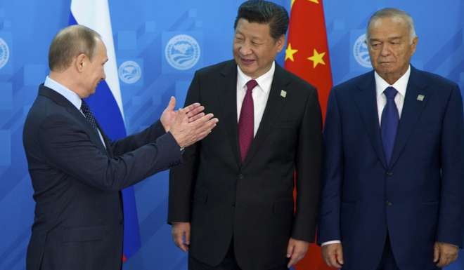 In this file photo taken on July 10, 2015, Russian President Vladimir Putin speaks to China's President Xi Jinping as Uzbekistan's President Islam Karimov, prepare to pose for a photo during the SCO (Shanghai Cooperation Organisation) summit in Ufa, Russia. Photo: AP