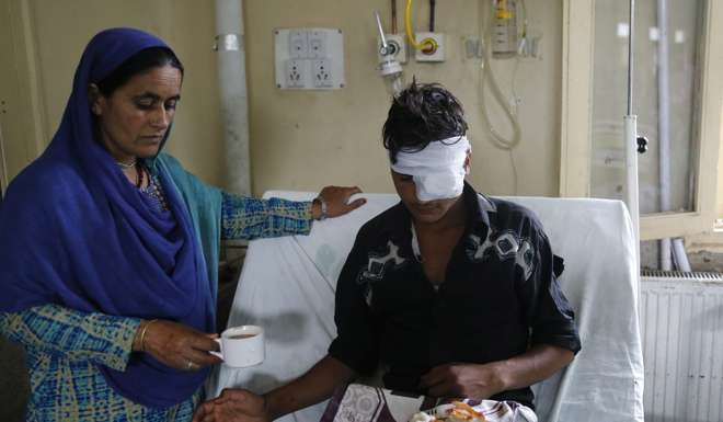 A relative of a pellet-injured Kashmiri Muslim boy helps him with tea as he receives treatment inside a local hospital in Srinagar. Photo: EPA