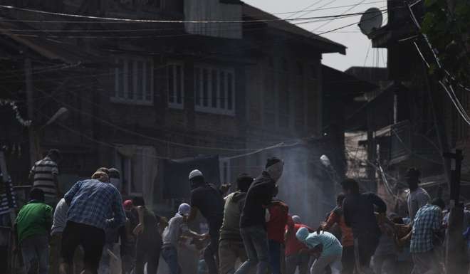 Masked Kashmiri Muslims run for cover as Indian police fire pellet guns at them during a protest. Photo: AP
