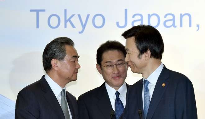 Chinese Foreign Minister Wang Yi, left, shakes hands with South Korean Foreign Minister Yun Byung-se, right, while Japanese Foreign Minister Fumio Kishida looks on following their first talks in more than a year. Photo: AFP