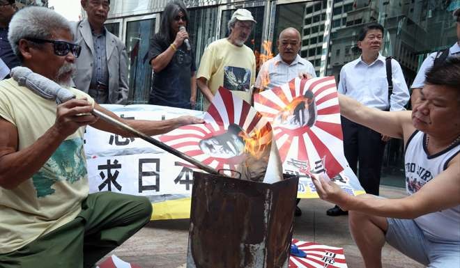 Members of the Action Committee for Defending the Diaoyus burn the Japanese flag with Hideki Tojo's picture on it outside the Japanese Consulate in Hong Kong to mark the end of the second world war. Photo: Dickson Lee