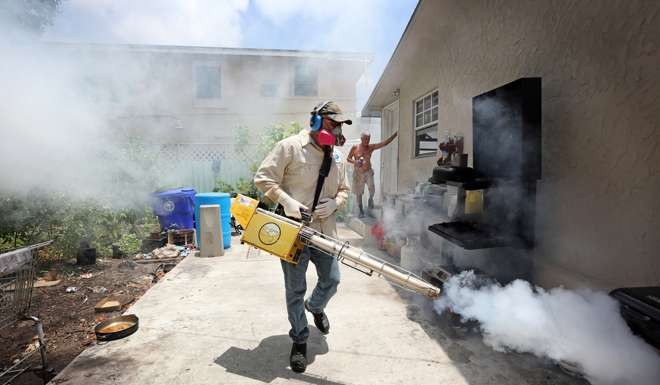 A mosquito inspector sprays around homes in Miami. Photo: TNS