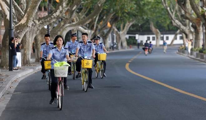 Security personnel ride bicycles on an empty road near the West Lake in Hangzhou on Wednesday. Photo: Reuters